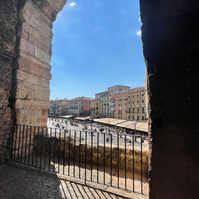 Picture shows a view through an archway to the street outside of the Arena di Verona