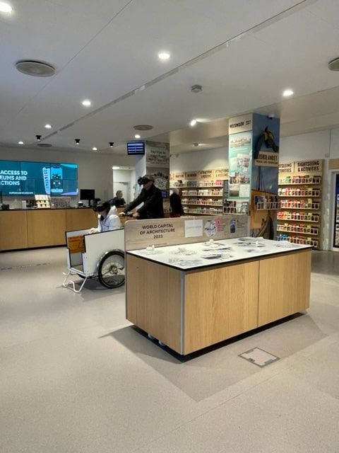 Inside of the Visitor Centre, showing plenty of room to manoeuvre and a man using an interactive display and VR headset.  The floor is flat and smooth and the area spacious, making it easy for the wheelchair user or other disabled traveller to get around.