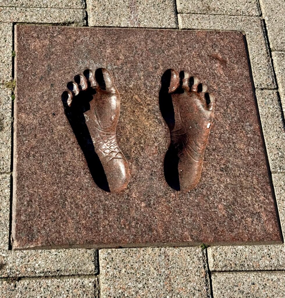 A bronze imprint of two feet set into the pavement outside Vilnius Cathedral.