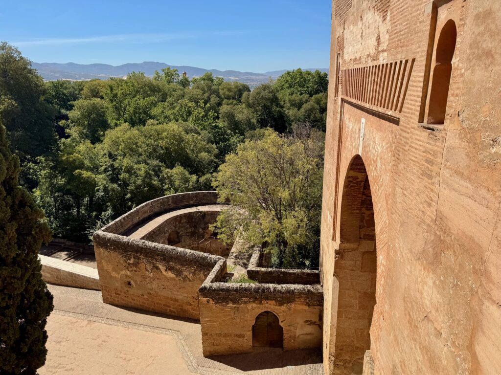 Views of the surrounding mountains and countryside framed by a large stone arch to the right of the image.