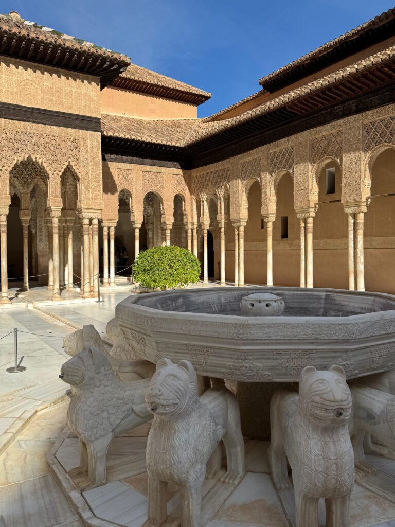 In the foreground is a fountain although no water is coming out. This large, circular stone centrepiece is supported by many stone lions. It is surrounded by a columned portico.